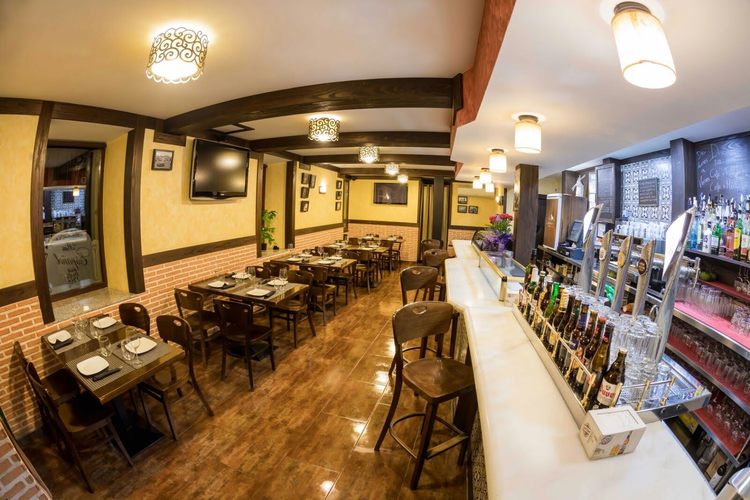 Comedor del Bar Español con vigas de madera, mesas y la barra de grifos